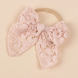 Close-up of pink lace baby headband with delicate bow and elastic nylon band