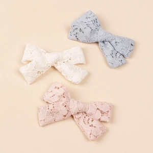 Close-up of floral lace texture on blue, beige, and pink bow hair clips for girls