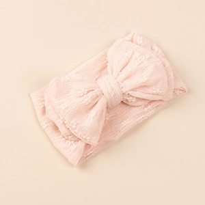 Détail du bandeau tricoté rose clair pour bébé avec un grand nœud et maille douce