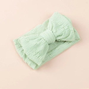 Gros plan détaillé d'un bandeau pour bébé vert menthe avec un grand nœud doux