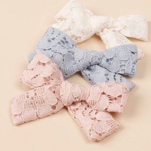Detailed lace texture on vintage hollow-out bow hair clips in cream, blue and pink