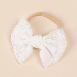 Detail of the white lace mesh bow on a soft nylon headband for infants and babies