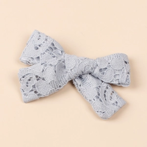 Close-up of light blue hollow lace bow hair clip with vintage embroidery texture