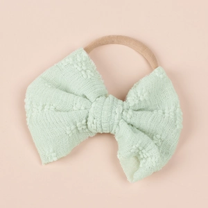 Detail of mint green lace bubble bow on elastic nylon headband for babies