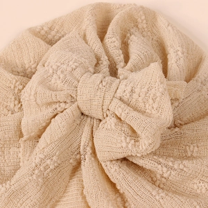 Detailed macro view of the textured knit fabric and oversized bow on the beige baby turban
