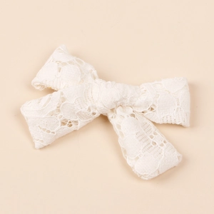Detailed close-up of white lace bow hair clip featuring intricate hollow floral patterns