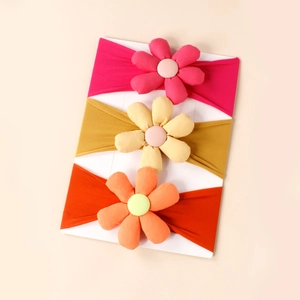 Close-up of three soft elastic baby headbands with 3D stuffed fabric flower decorations