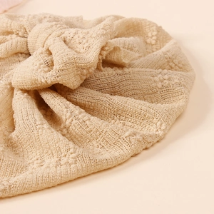 Close-up of soft lace mesh texture and knot detail on a beige baby turban hat