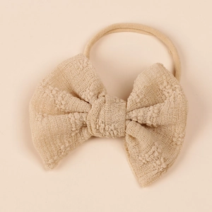 Detailed view of beige knit mesh baby bow headband made with soft nylon material