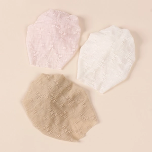 Detail of three infant beanies in pink, white, and coffee with textured floral fabric