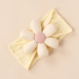 Close-up of baby headband with a soft yellow elastic strap and white padded cotton flower