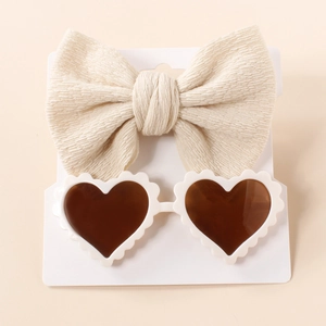 Detail of baby set with beige waffle knit bow headband and white heart-shaped sunglasses