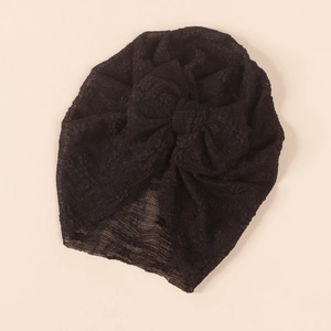 Detailed macro view of the intricate lace mesh texture and bow design on the black turban