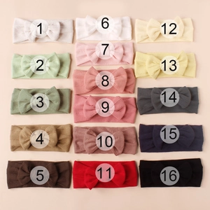 Collection of 16 colorful ribbed knit elastic baby headbands with large bows in a 4x4 grid