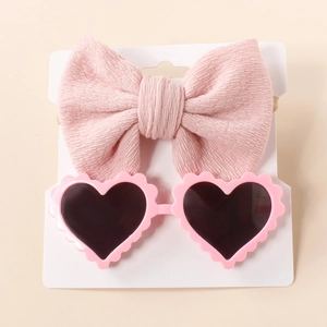 Detail of pink knit bow headband and heart-shaped sunglasses set for newborns