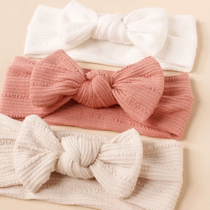 Three-piece set of soft ribbed baby headbands with large bows in neutral colors
