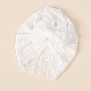 Detailed view of white baby turban featuring breathable lace floral pattern and large bow