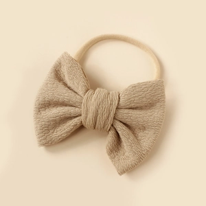 Detail of baby waffle knit bow headband in beige featuring soft high elastic nylon band
