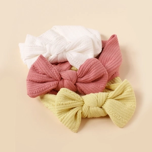 Three-pack of soft ribbed knit baby bow headbands in white, pink, and pale yellow