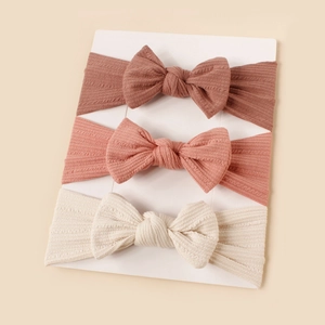 Detailed set of three soft ribbed knit baby headbands with handmade bows on display card