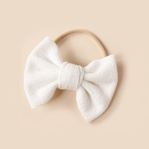 Detail of white textured fabric bow on ultra-soft stretch nylon baby headband