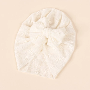 Detail view of cream baby turban with a large soft bow and delicate textured knit fabric
