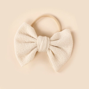 Close-up of cream knit bow baby headband with soft nylon elastic hairband detail