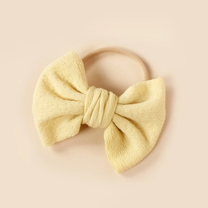 Detail of soft ribbed pale yellow fabric bow on high-elastic nylon headband for infants