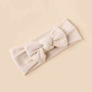 Detailed close-up of ribbed texture beige baby headband with large soft bow accent