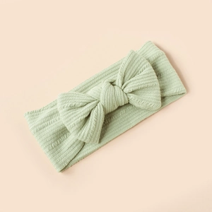 Detailed close-up of light green knit baby headband featuring soft ribbed textures and bow