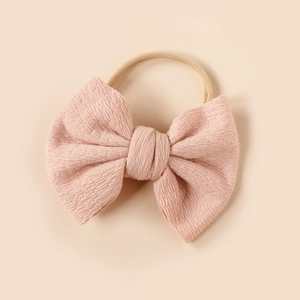 Detail of pink knitted bow with textured fabric on a soft nylon baby headband