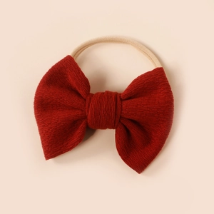 Close-up of a red knitted baby bow headwrap with soft elastic nylon fabric texture
