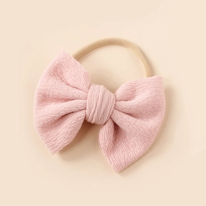 Detail of soft pink textured knit bow on high-elasticity nylon headband for baby girls
