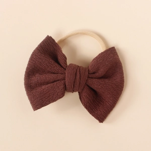 Detailed texture of dark brown ribbed knit fabric bow on soft nylon baby headband