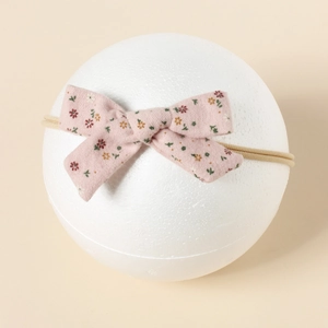 Nahaufnahme eines Baby-Nylon-Stirnbands mit rosa Blumenmuster-Schleife auf Requisite
