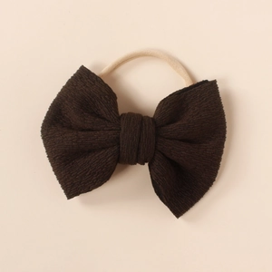 Detailed macro view of dark brown ribbed fabric bow on a soft nude nylon headband