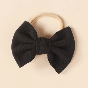 Close-up of black ribbed fabric bow on a soft nude nylon headband for infants