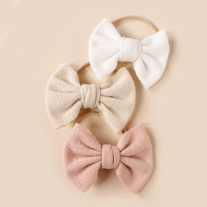 Three-pack soft ribbed knit baby headbands with bow in white, beige, and peach colors