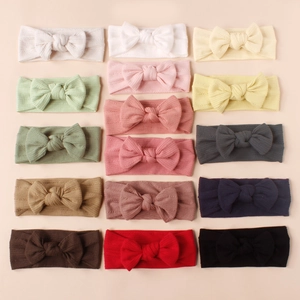 Flat lay of 15 colorful striped knit baby bow headbands in various pastel and bold tones