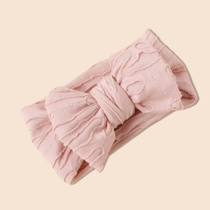 Vue détaillée du bandeau pour bébé en maille jacquard rose avec un grand nœud