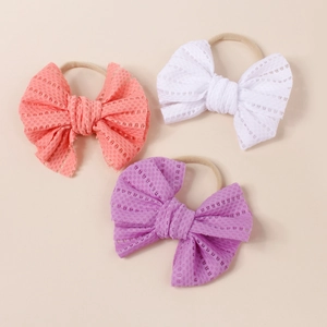 Detailed view of three mesh bow headbands in pink, white, and purple for baby girls