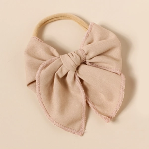 Détail du bandeau bébé en lin avec nœud et finition de bordure rose délicate