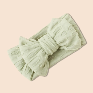Gros plan d'un bandeau bébé en maille vert clair avec un grand nœud décoratif doux