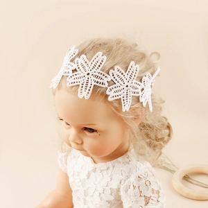 Vue détaillée de la broderie en dentelle florale blanche sur un bandeau doux pour bébé