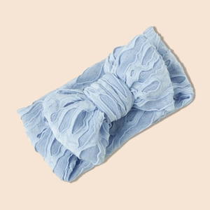 Détail du bandeau bébé en tricot bleu clair avec un nœud double épaisseur texturé