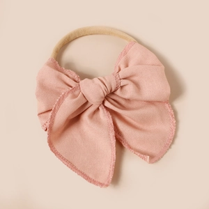 Détail d'un bandeau à nœud en lin rose avec élastique en nylon souple et bordure surjetée