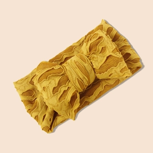 Gros plan d'un bandeau bébé en maille jaune avec nœud texturé et motif jacquard