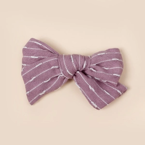 Vue détaillée du nœud en tissu rayé violet avec coutures blanches et texture en lin