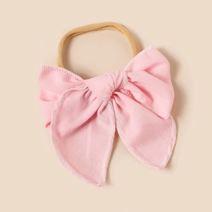 Gros plan du nœud en lin rose sur bandeau élastique en nylon beige pour bébés et filles