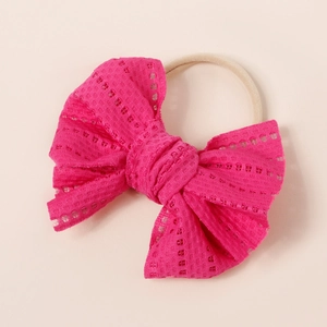 Close-up of rose red lace bow headband with soft beige elastic nylon band for infants